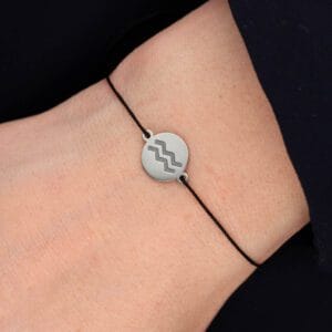 Bransoletka dla Wodnika na sznurku z celebrytką. Bransoletka srebrna na czarnym sznurku na ręce