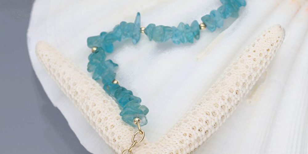 Złota bransoletka damska goldfilled z sieczką z apatytu i przedłużką zakończoną kuleczka położona na muszli